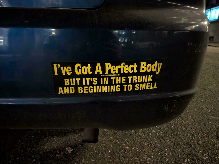 A funny bumper sticker on a dark blue car reads, I've Got A Perfect Body, but it's in the trunk.