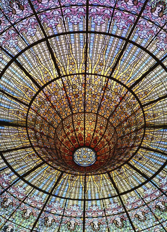 Intricate stained glass ceiling with colorful patterns and faces creating a misleading and confusing photo effect.