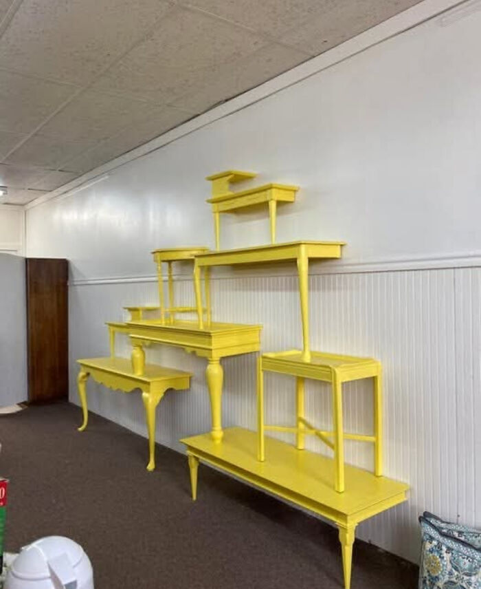 Bright yellow painted tables arranged in a bizarre tiered wall display, an example of questionable DIY projects.