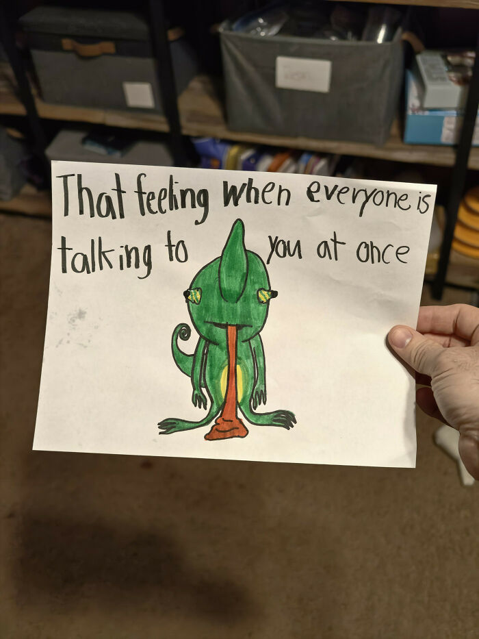 A hand holds up a drawing that reads, That feeling when everyone is talking to you at once, showing a chameleon puking. A relatable post for dads.