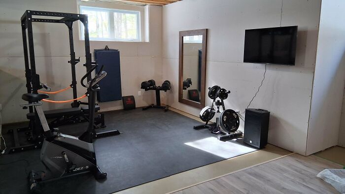 A home gym with an exercise bike, weight rack, and wall-mounted TV, dedicated to dads' fitness journeys.