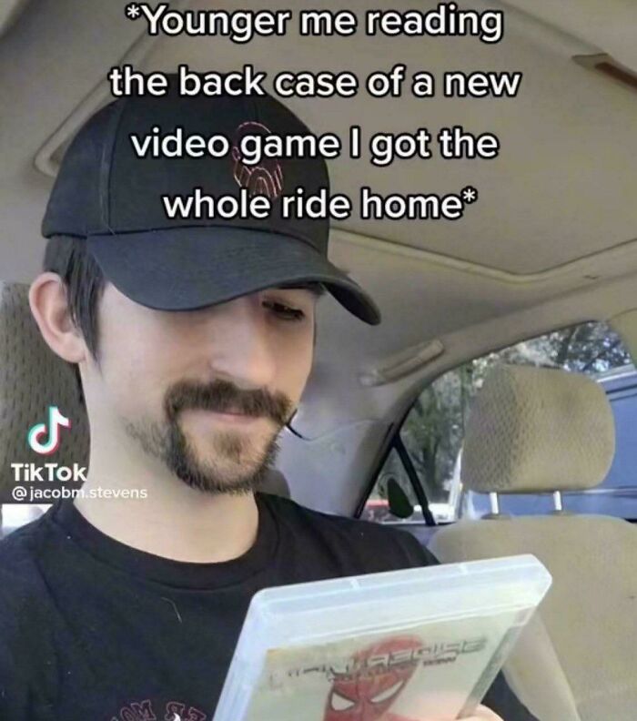 Man reading video game case in car, capturing a relatable moment from posts and memes about our lives.