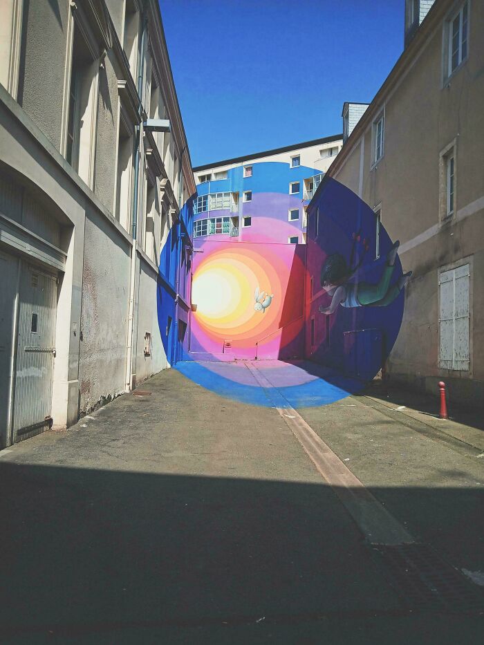 A vibrant, colorful street art mural creating an optical illusion of a tunnel and a floating figure, an interesting photo.