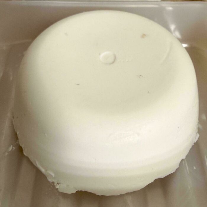 Close-up of a white, dome-shaped food item, possibly cheese or panna cotta, showcasing frugal tips for the economy.