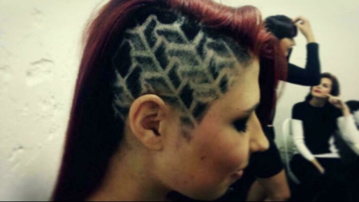 Intricate geometric hair design shaved on side of red-haired person
