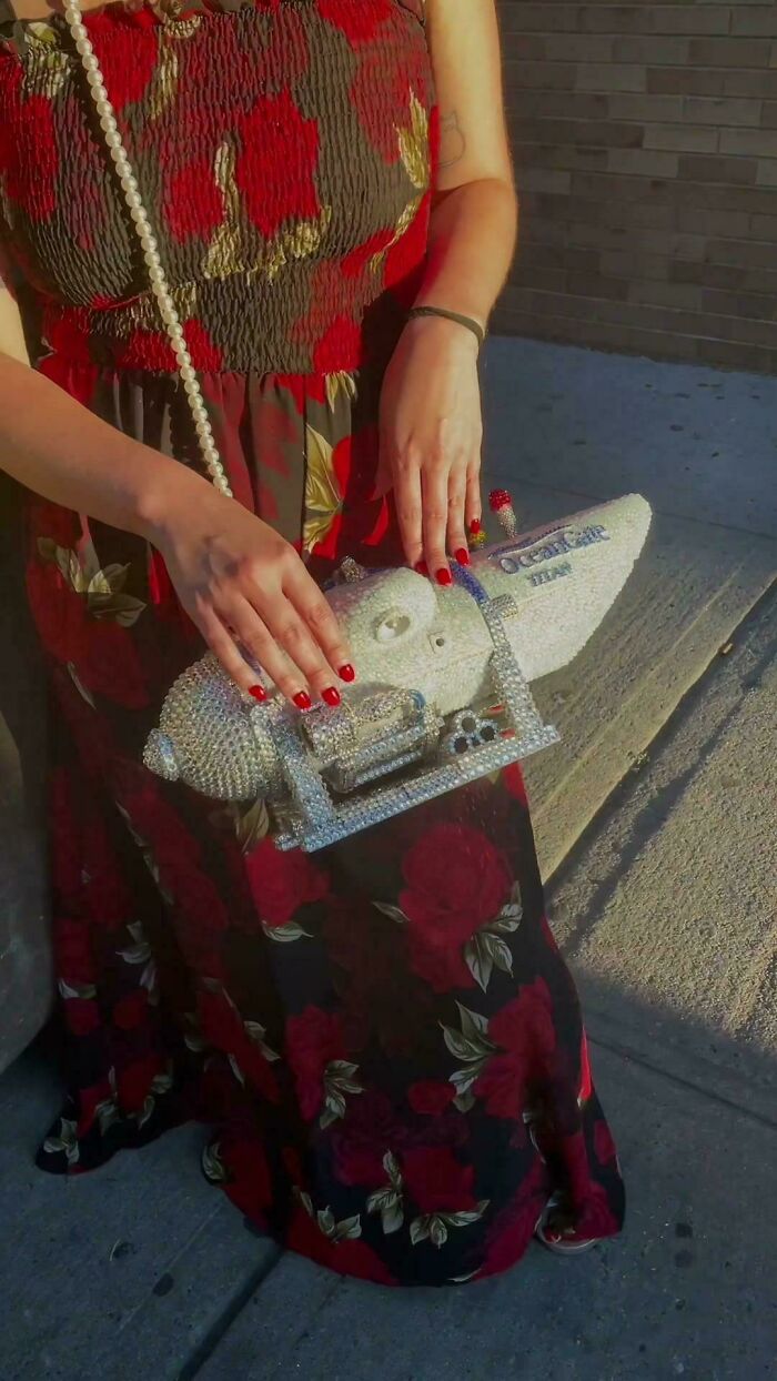 Woman holding bejeweled Ocean Spray cranberry bag with floral dress