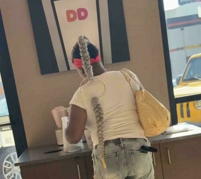 Woman with unique braided hairstyle resembling a tail at Dunkin Donuts
