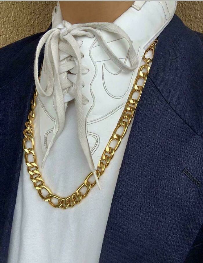White sneaker worn as a necktie with gold chain highlighting questionable fashion