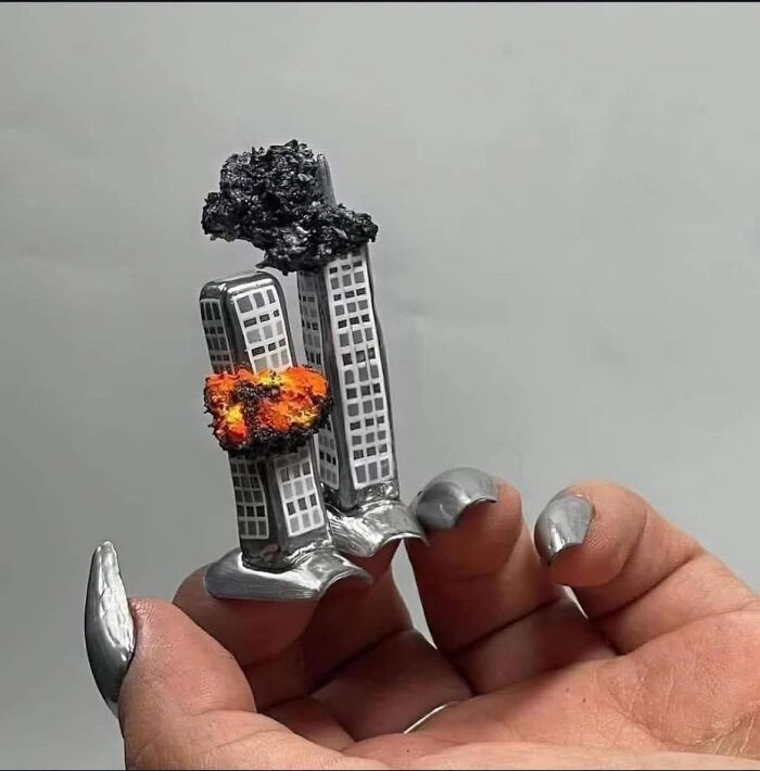 Tiny metal sculpture of burning twin towers held in hand
