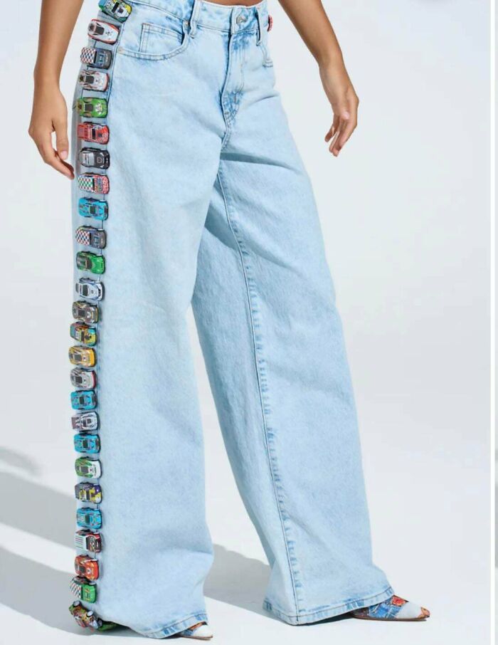 Wide denim jeans decorated with a row of small toy cars on the side
