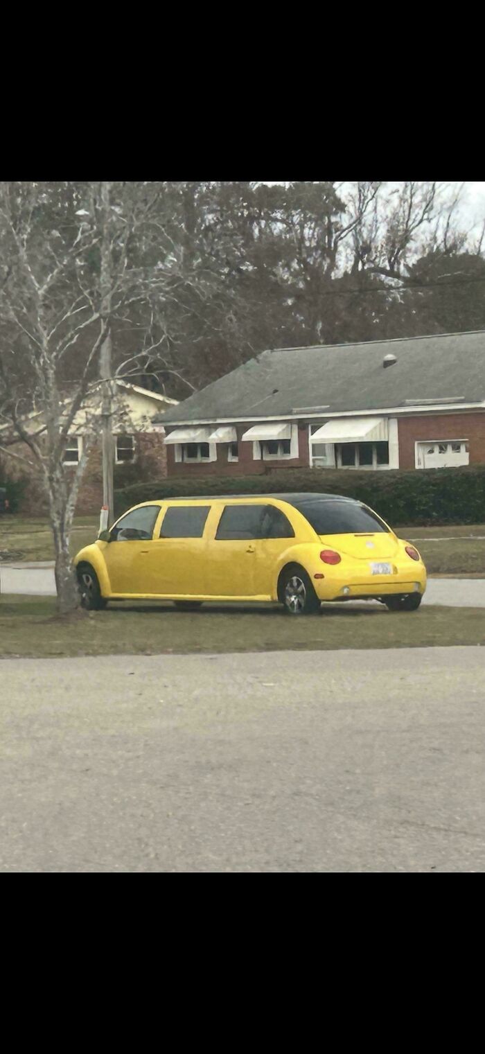 Yellow stretched limousine car parked on grass near tree in residential area