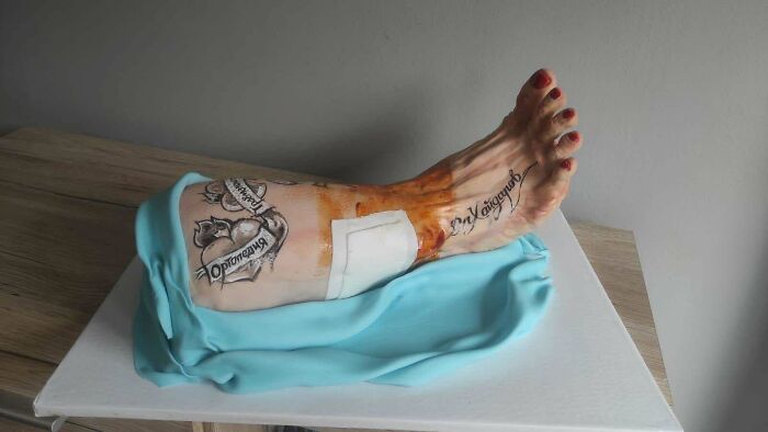 Realistic leg cake with tattoos and bandage showcasing impressive skill waste