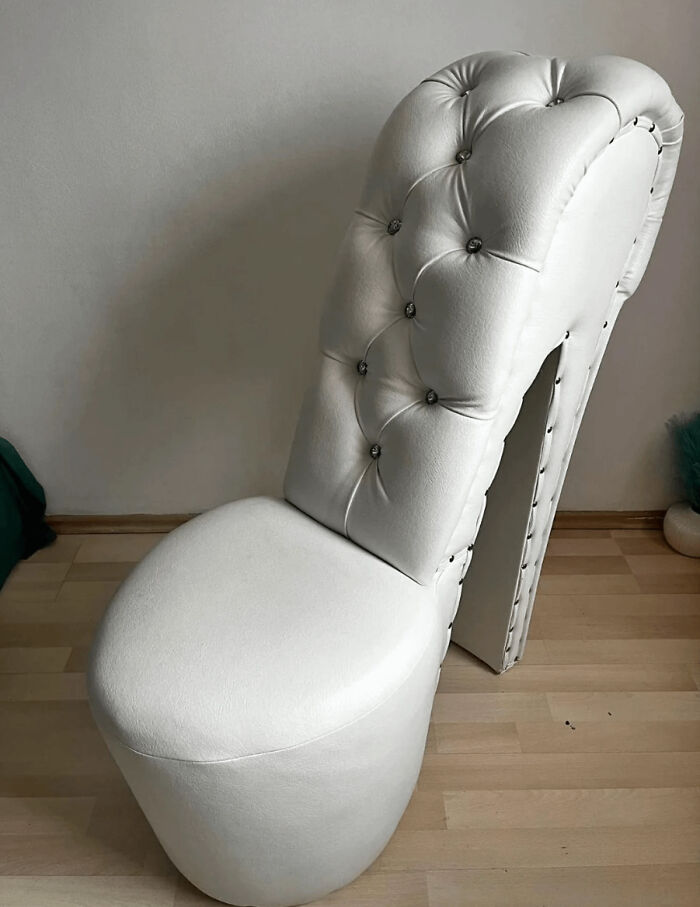 White leather chair shaped like a high-heeled shoe with tufted back