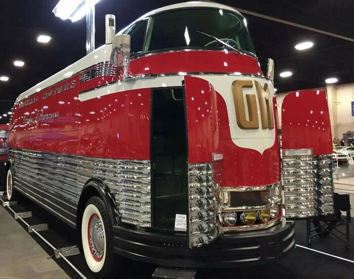 A red and white retrofuturistic GM Futurliner bus with chrome details and open doors, imagining the future.