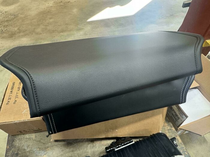 A close-up of a new black car part with white stitching, highlighting the detailed work of car mechanics.