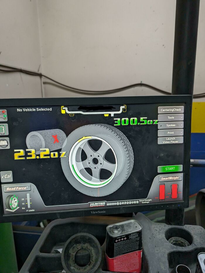 A car mechanic adjusting a car wheel balancing on a screen, dealing with an unusual car issue.
