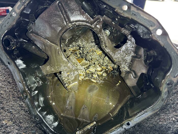 Damaged car engine component with debris, showcasing severe car mechanics problems.