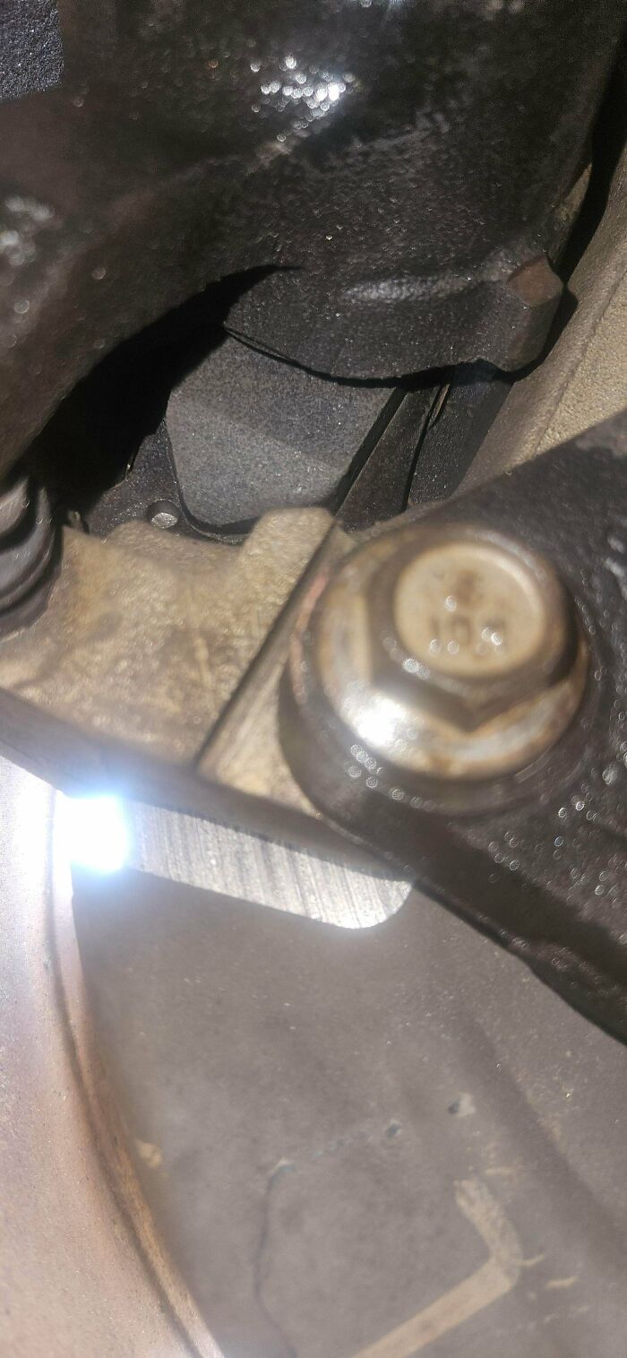 A close-up of a car part, showing a bolt and metal components, for car mechanics documentation.