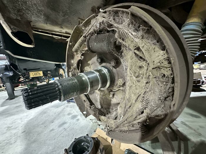 A car brake drum, heavily caked with dust and cobwebs, indicating significant wear for car mechanics.