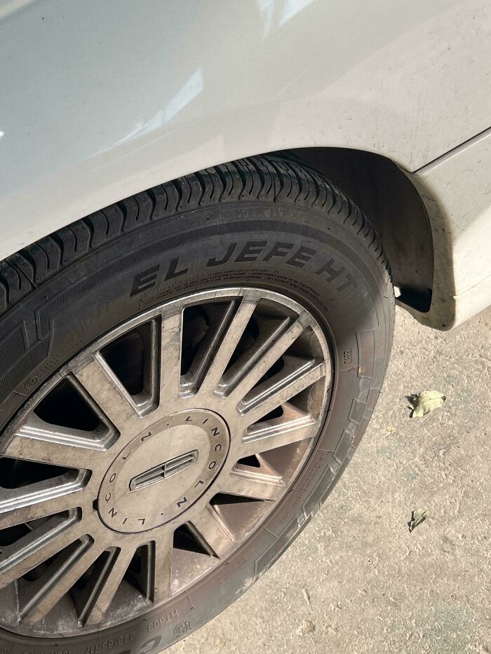 Close-up of a car tire with 'EL JEFE HT' visible on the sidewall, highlighting the car mechanics work.