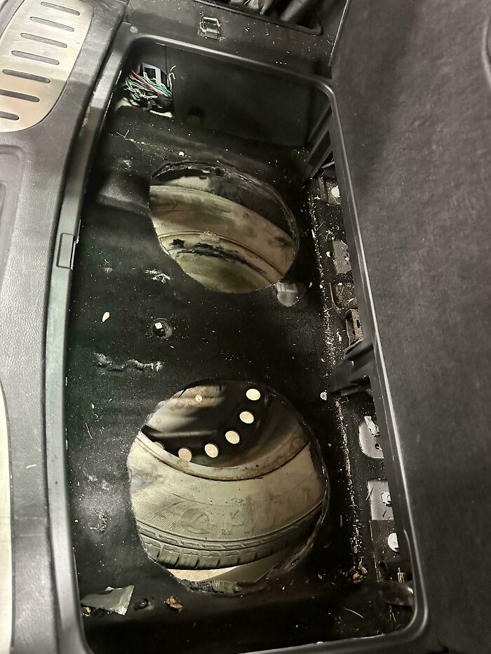 Car mechanics discover two tires improperly stored in a car's trunk, causing damage.