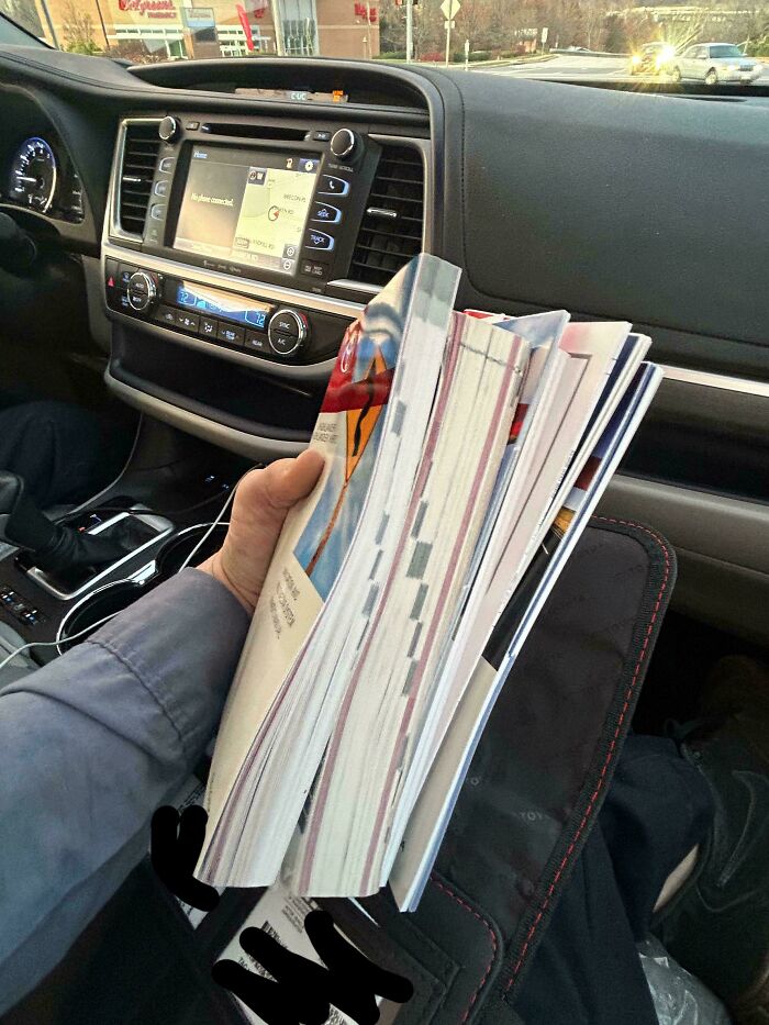 Car mechanics encounter a stack of service manuals in a vehicle, a common sight.