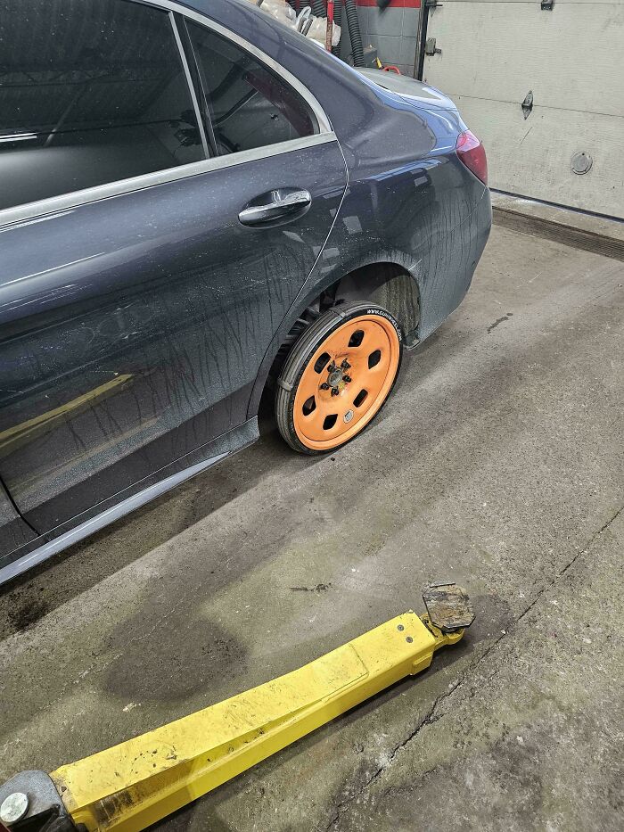 A car with a bright orange spare wheel, a sight car mechanics might deal with in their daily work.
