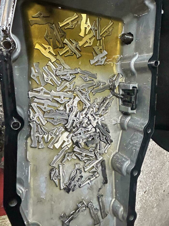 Car mechanics find numerous metal fragments in an oil pan, illustrating significant engine damage in car repair.