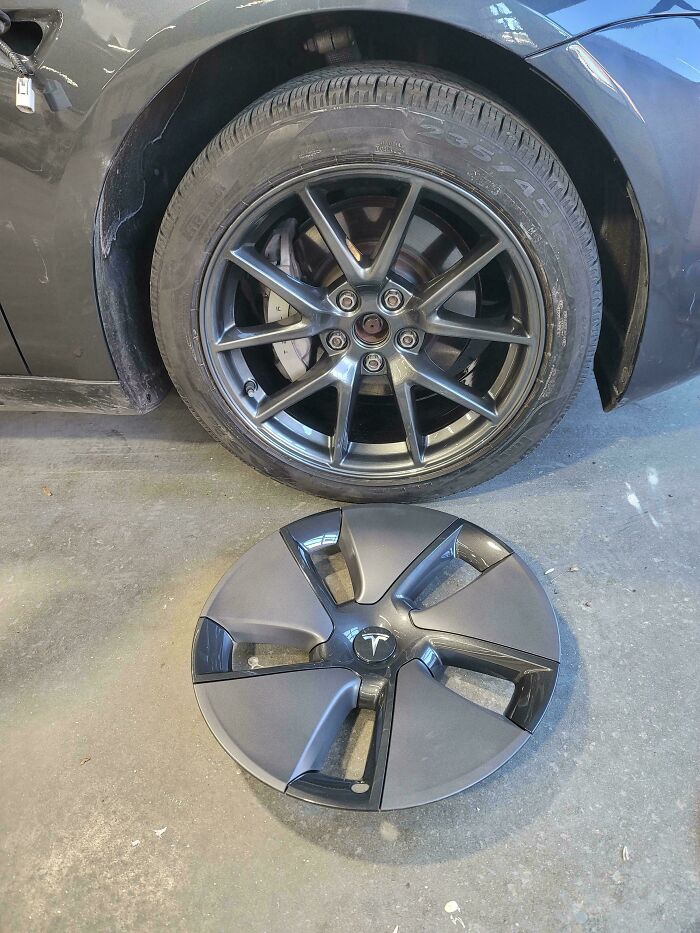 A car wheel with a detached hubcap on the ground, a common sight for car mechanics dealing with repairs.