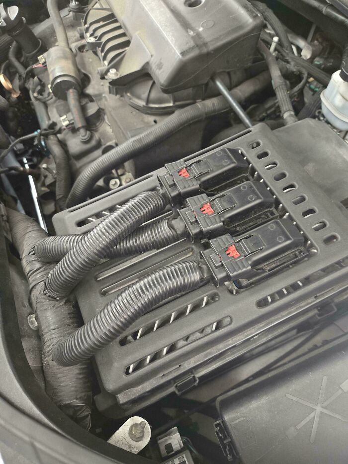 Close-up of organized wiring and connectors in a car engine bay, demonstrating complex car mechanics work.