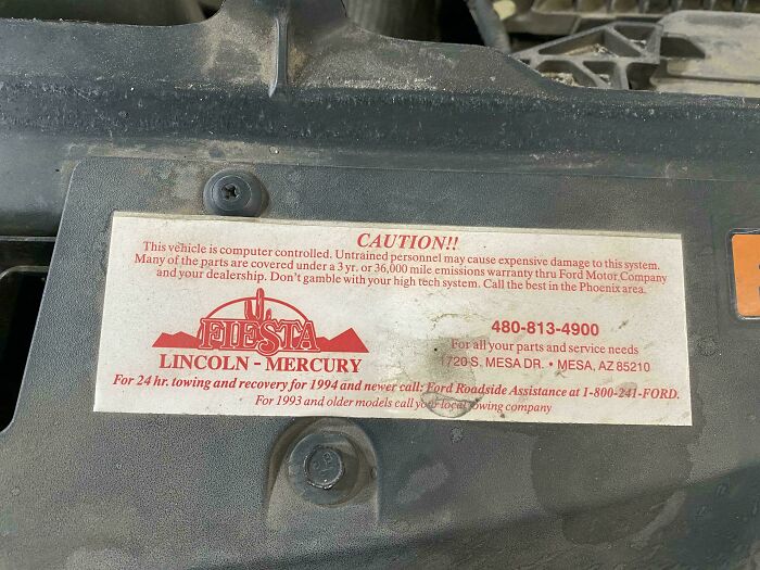 A close-up of a vintage Ford warning sticker under the hood, showcasing the old car mechanics advice.