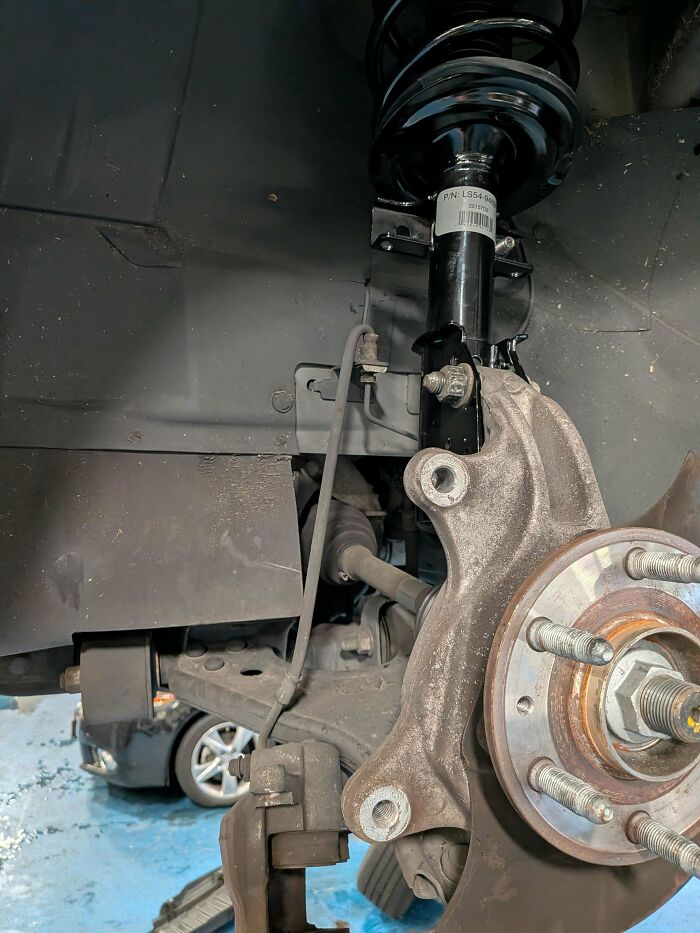 Close-up of a car's suspension and wheel assembly, part of a car mechanics repair job.