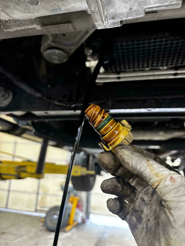 A car mechanic holds a dirty car part, illustrating the unusual issues car mechanics encounter.