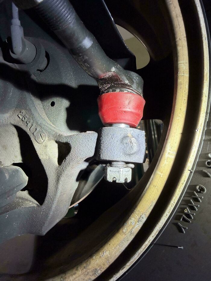 A close-up of a car's suspension component, showing a red bushing and tire, a typical scene for car mechanics.