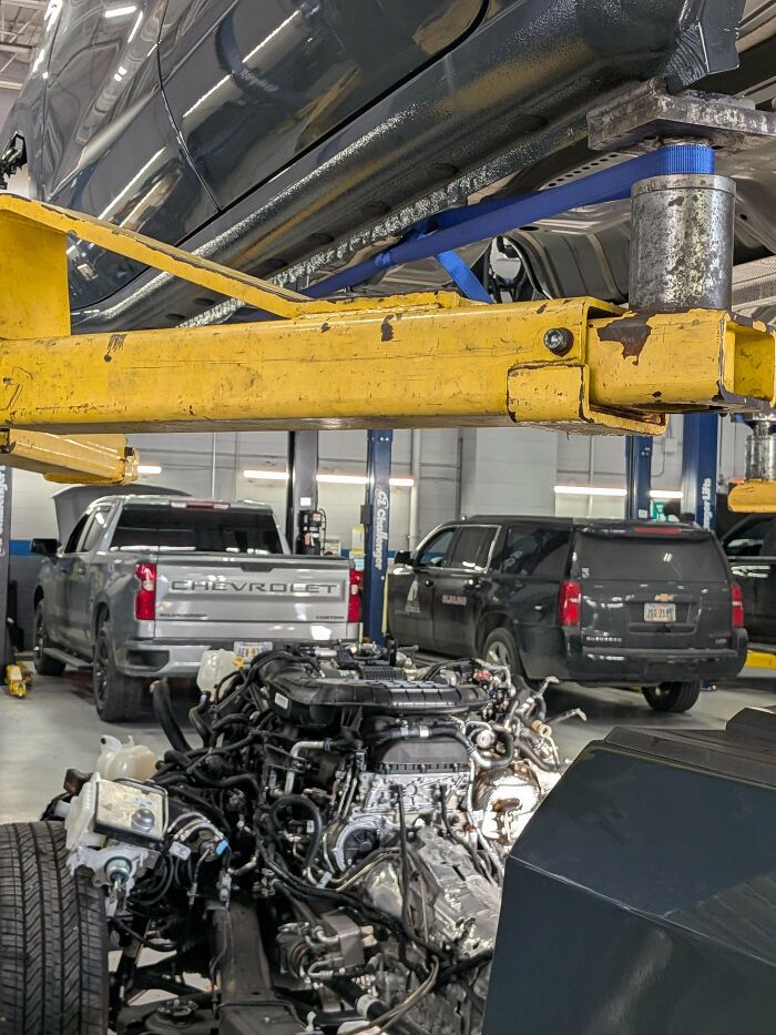 A car mechanic dealing with a car engine removed from a vehicle and placed on the garage floor, illustrating a major repair.