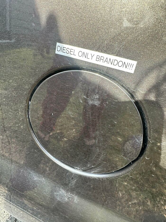A car fuel cap with a prominent sticker saying DIESEL ONLY BRANDON!!!, a detail car mechanics might photograph.