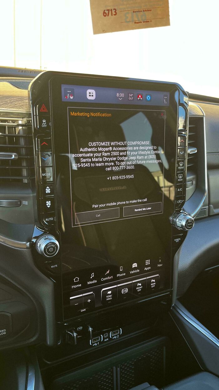 Car mechanics encounter a marketing notification on a car's infotainment system, an unusual in-car pop-up.