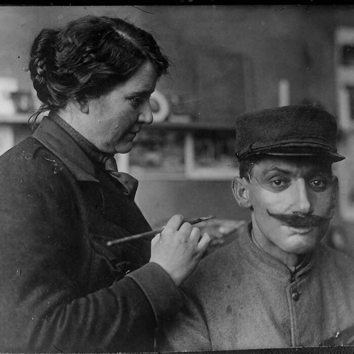 An intriguing historical photo of a woman applying makeup to a man's face, a glimpse into past daily life.