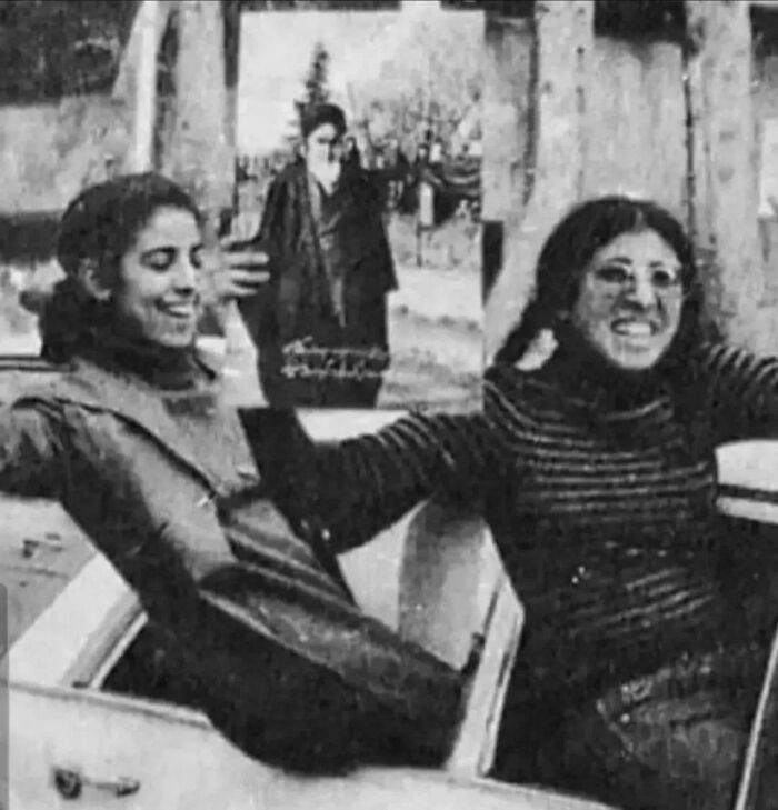 Two smiling women in a car, with a historical figure's poster in the background, showcasing a snapshot from important historical photos.