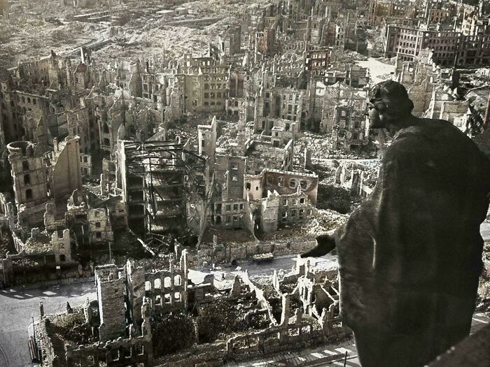 An aerial view of a city completely destroyed by bombing, with a figure in the foreground looking out, representing powerful historical photos.