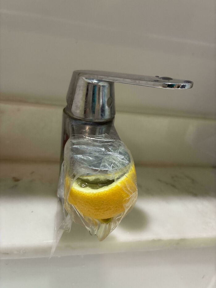 Faucet handle covered with plastic wrap and lemon slice demonstrating redneck engineering creativity.