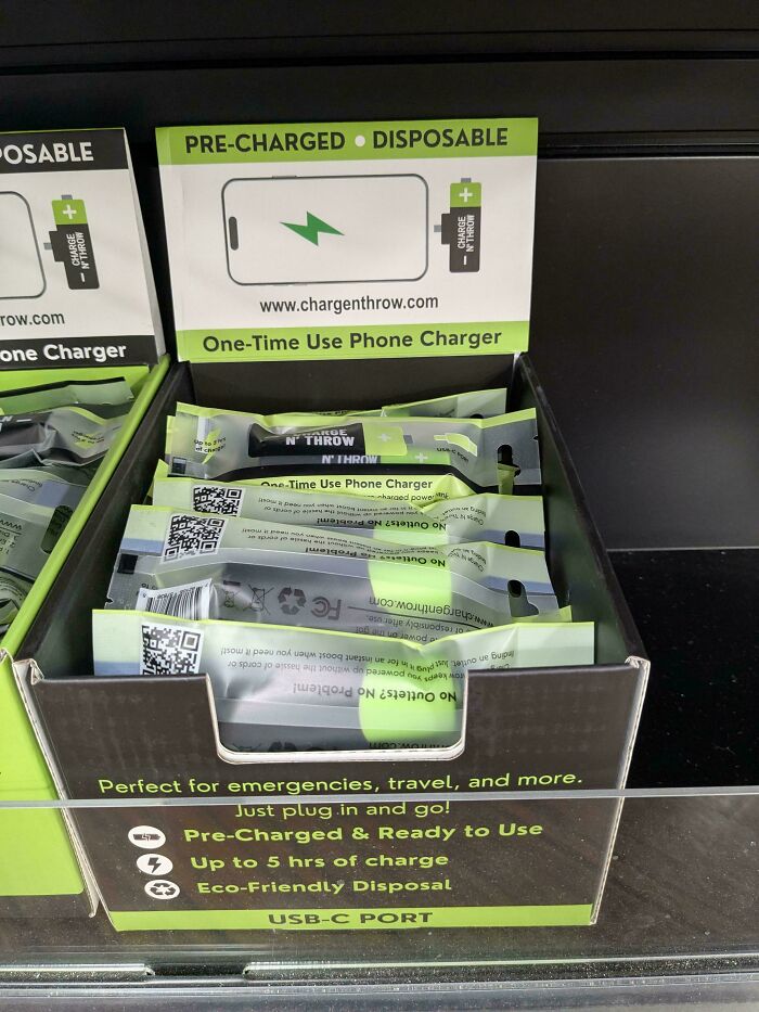 A display box of disposable phone chargers, emphasizing wasteful consumerism and single-use products.