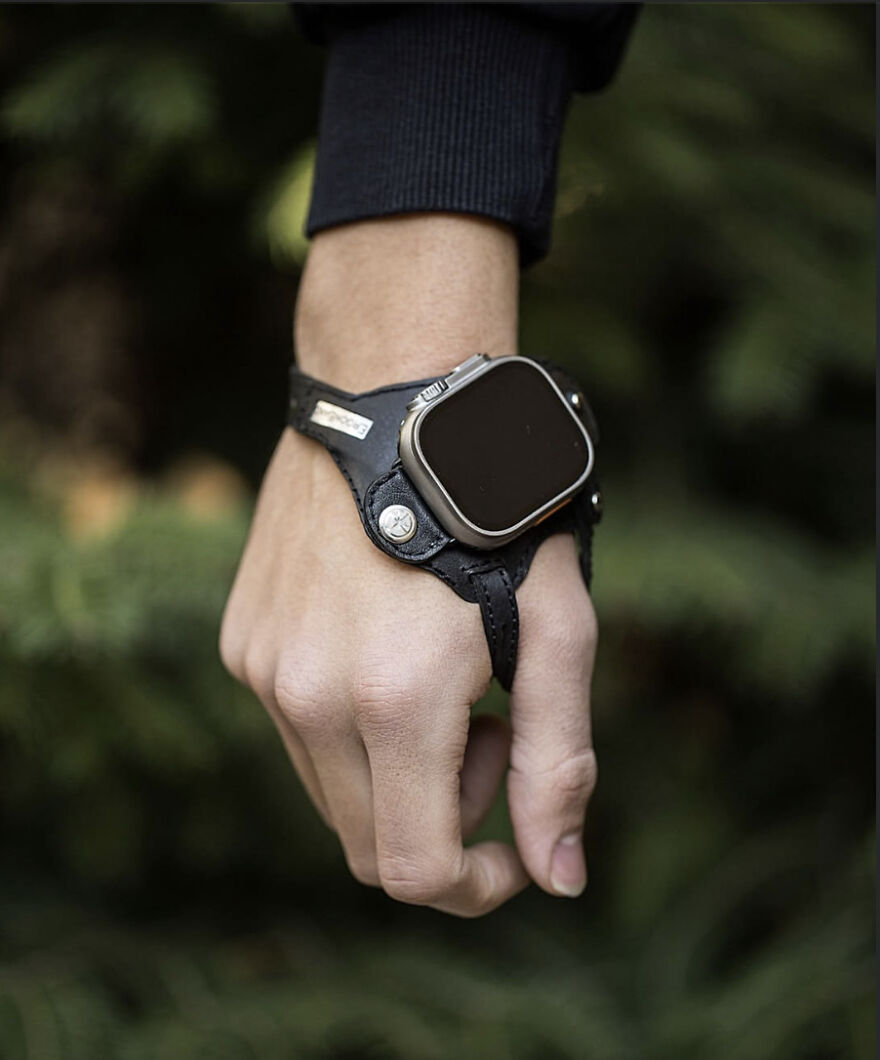 Smartwatch attached to an unusual leather hand strap, showcasing a designer product that is difficult to use.