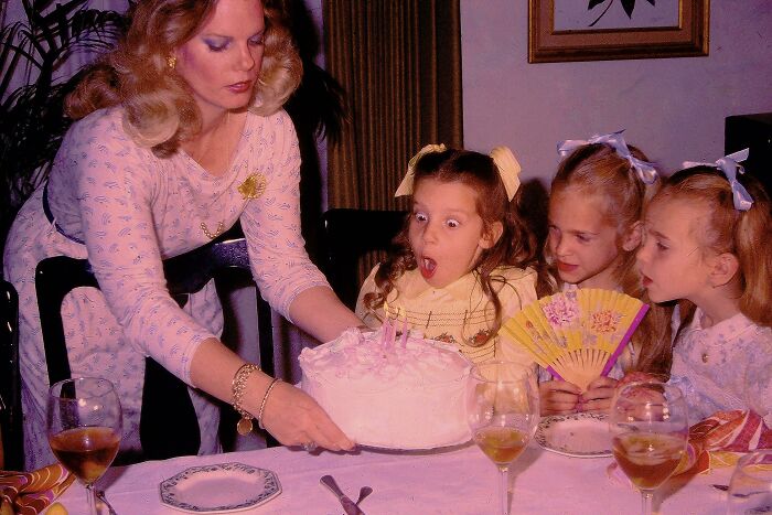 Vintage childhood birthday party with a girl surprised by cake, capturing hilariously awkward childhood moments shared by people.