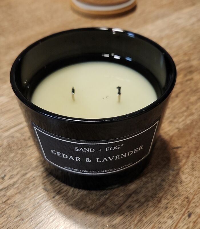 Black Cedar and Lavender candle with two unlit wicks on a wooden table, showcasing a clever product design solution.