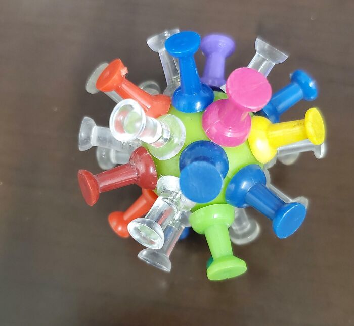 Colorful pushpins arranged on a green ball, showing a creative and genius idea for organizing pushpins efficiently.