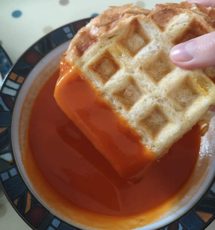Waffle used as a grilled cheese sandwich dipped into tomato soup, showcasing a genius idea to solve an annoying problem.