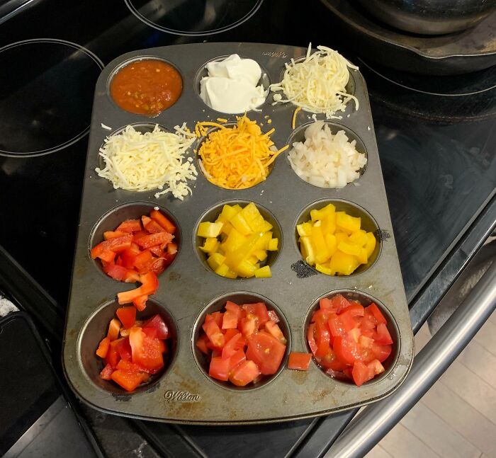 Muffin tin used to organize different chopped vegetables, cheese, salsa, and sour cream as a genius kitchen solution.