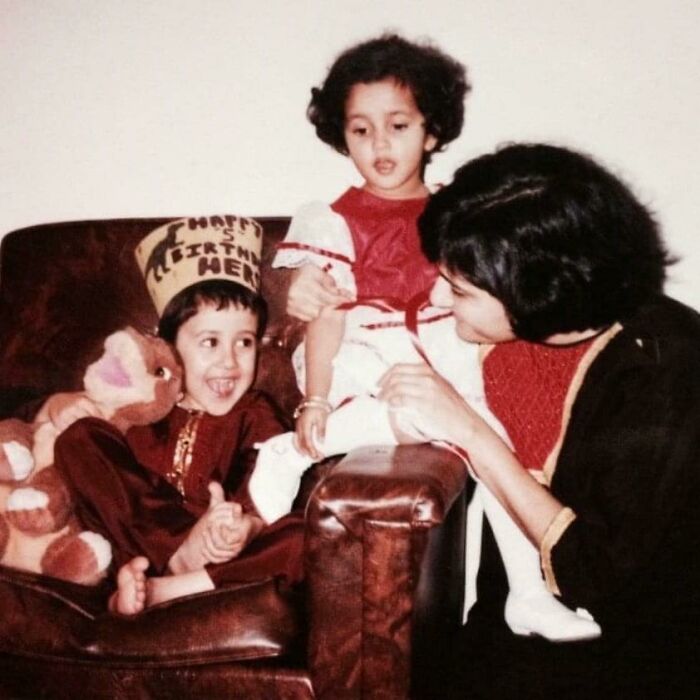 Two children and a woman share a moment on a couch in a hilariously awkward childhood pic from a nostalgic family setting.