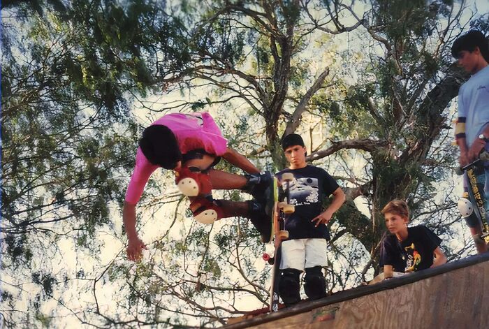 Kids at a skate park, one performing an awkward jump while others watch, capturing hilariously awkward childhood moments.